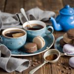 Blue teapot with 2 cups sharing a saucer, cookies, and a crumpled napkin