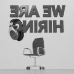 image of office chair and headphones with the words We Are Hiring spelled backward.
