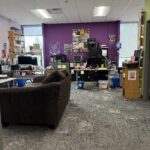 Photo of the GRCGED office with a brown couch, 2 desks, purple walls with posters.